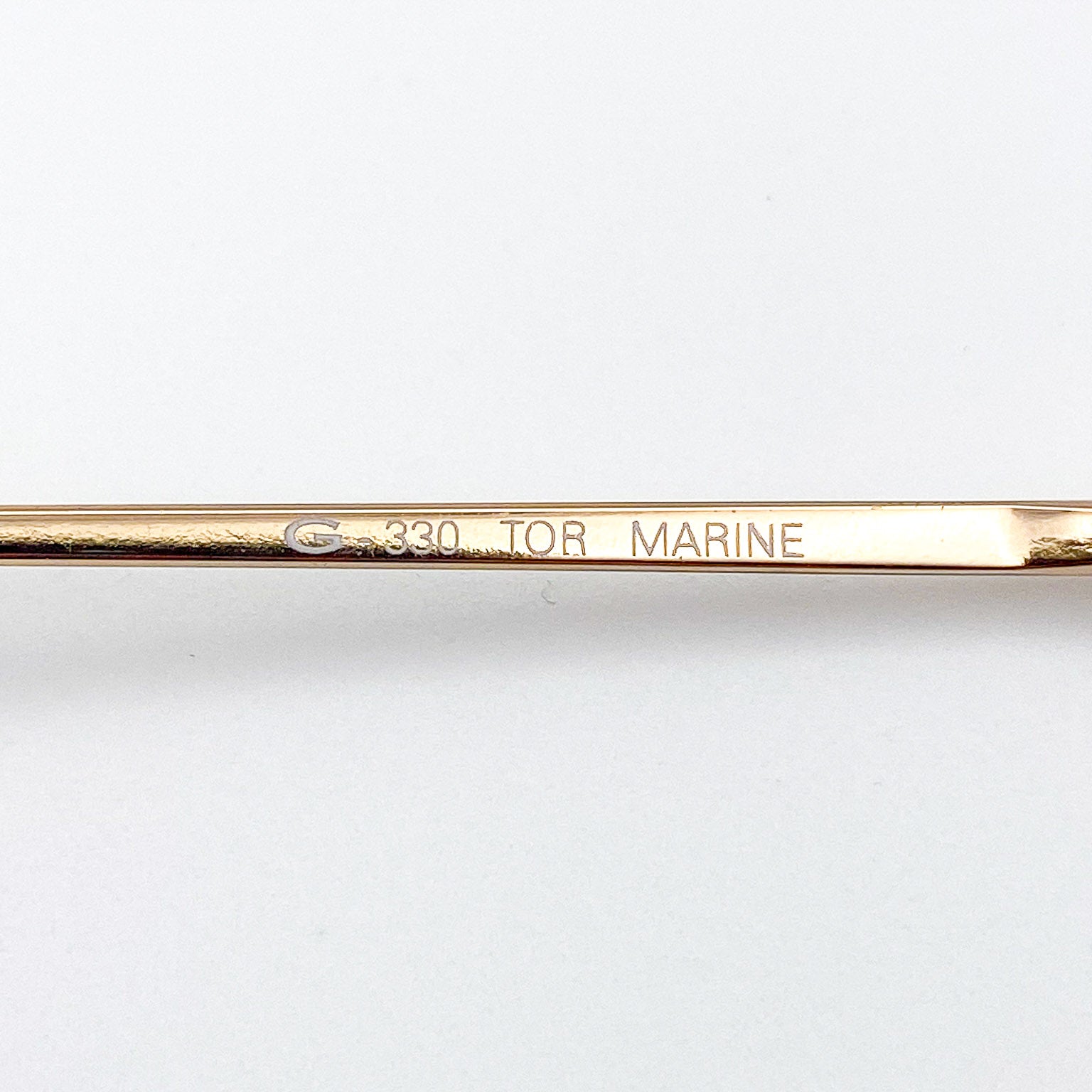 Gold-colored temple with engraved text on a white background