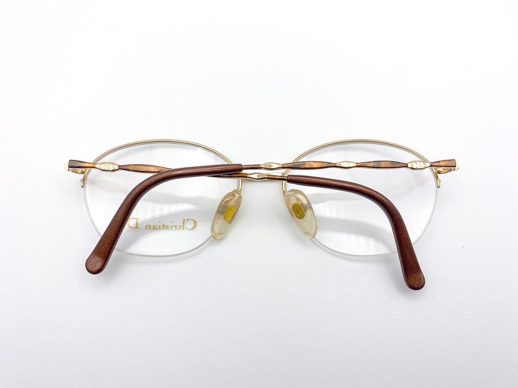 Pair of eyeglasses with gold frame and brown temple tips on a white background