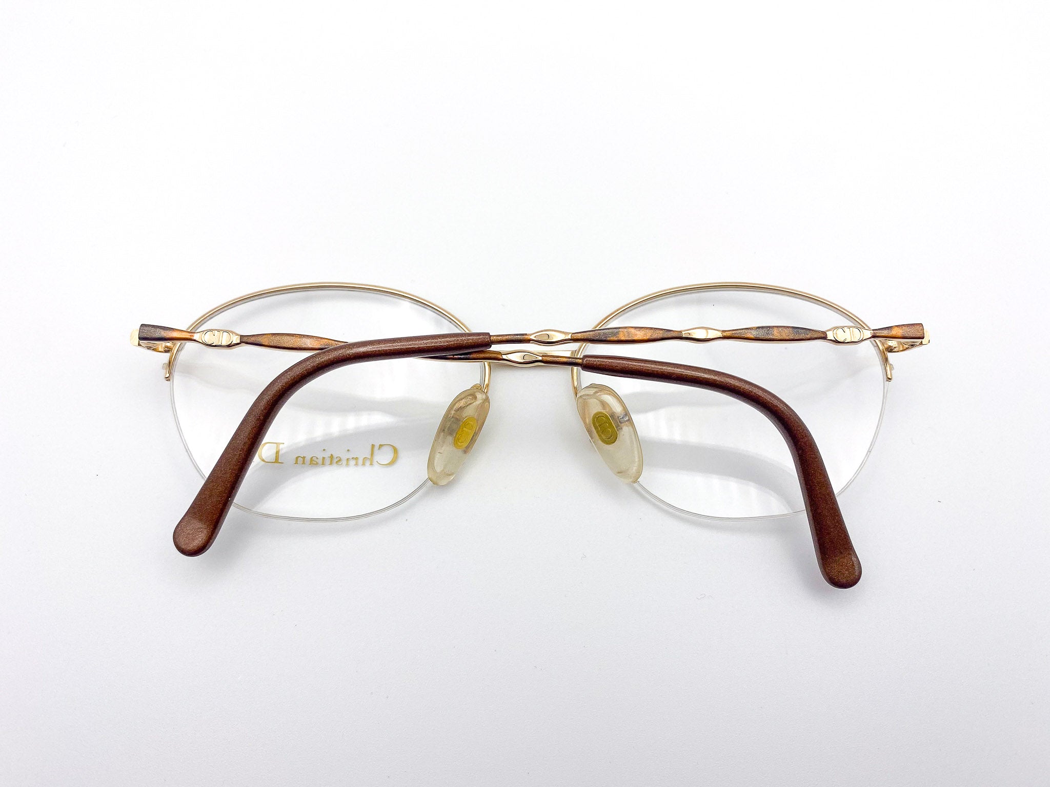 Pair of eyeglasses with gold frame and brown temple tips on a white background