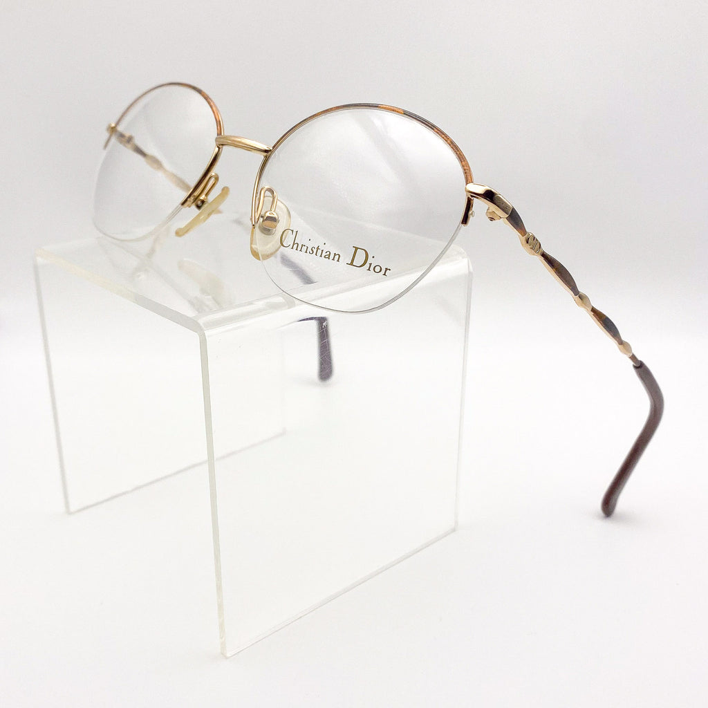 Round eyeglasses with gold frame and 'Christian Dior' logo on a white background