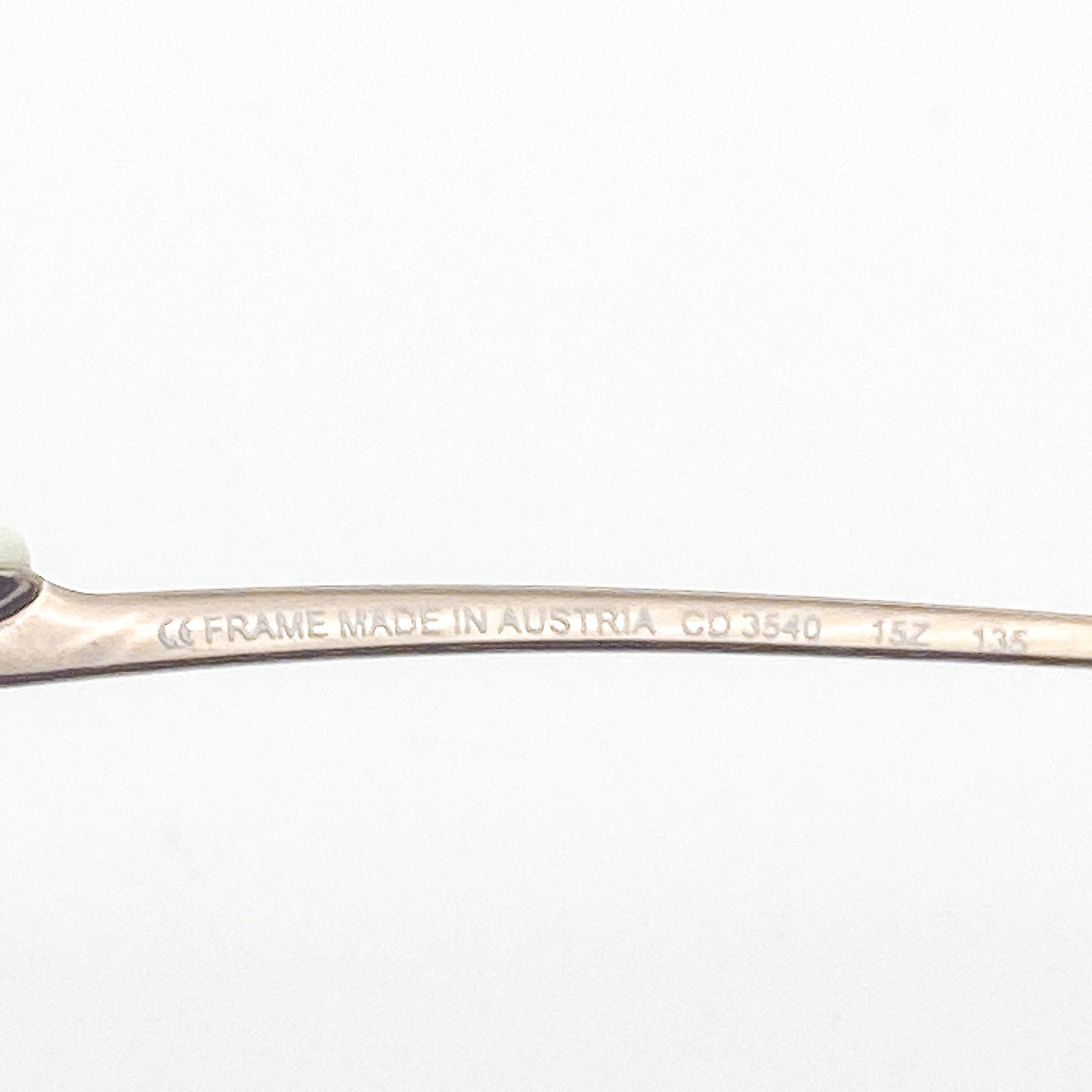 Close-up of a eyeglasses temple frame with 'Made in Austria' engraving on a white background