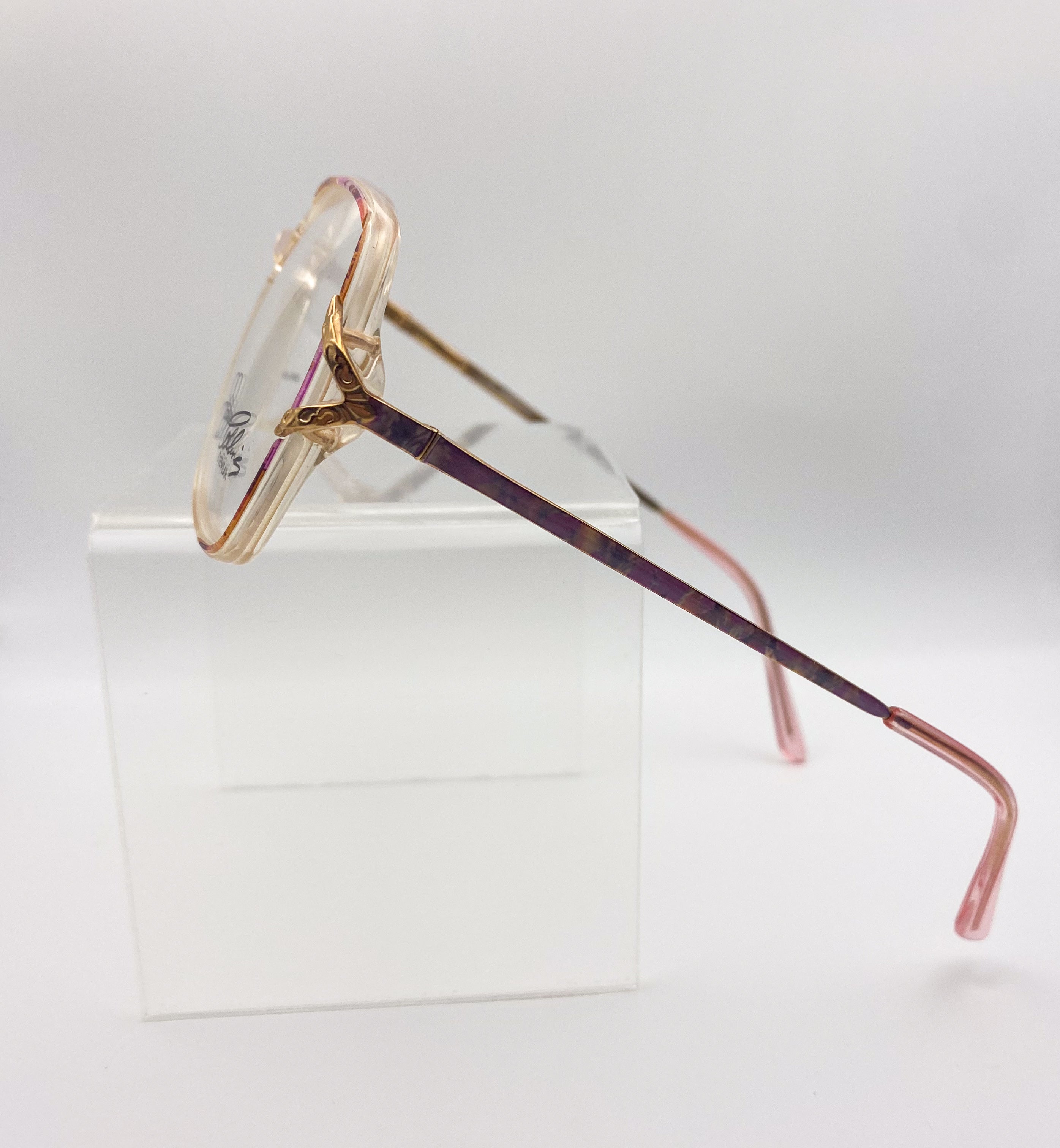 Eyeglasses with gold frame and purple arms on a white background