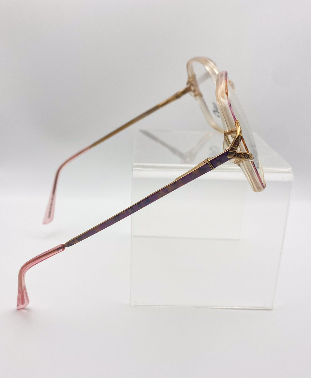 Eyeglasses with a unique frame design on a clear stand against a white background