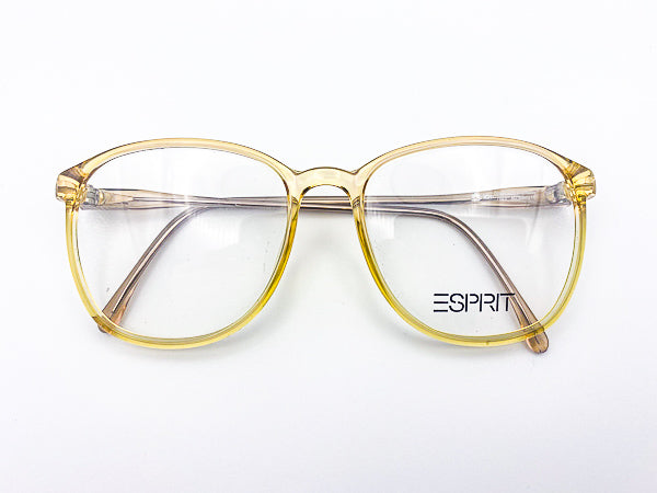 Translucent yellow 1980s eyeglasses with 'Esprit' logo on a white background