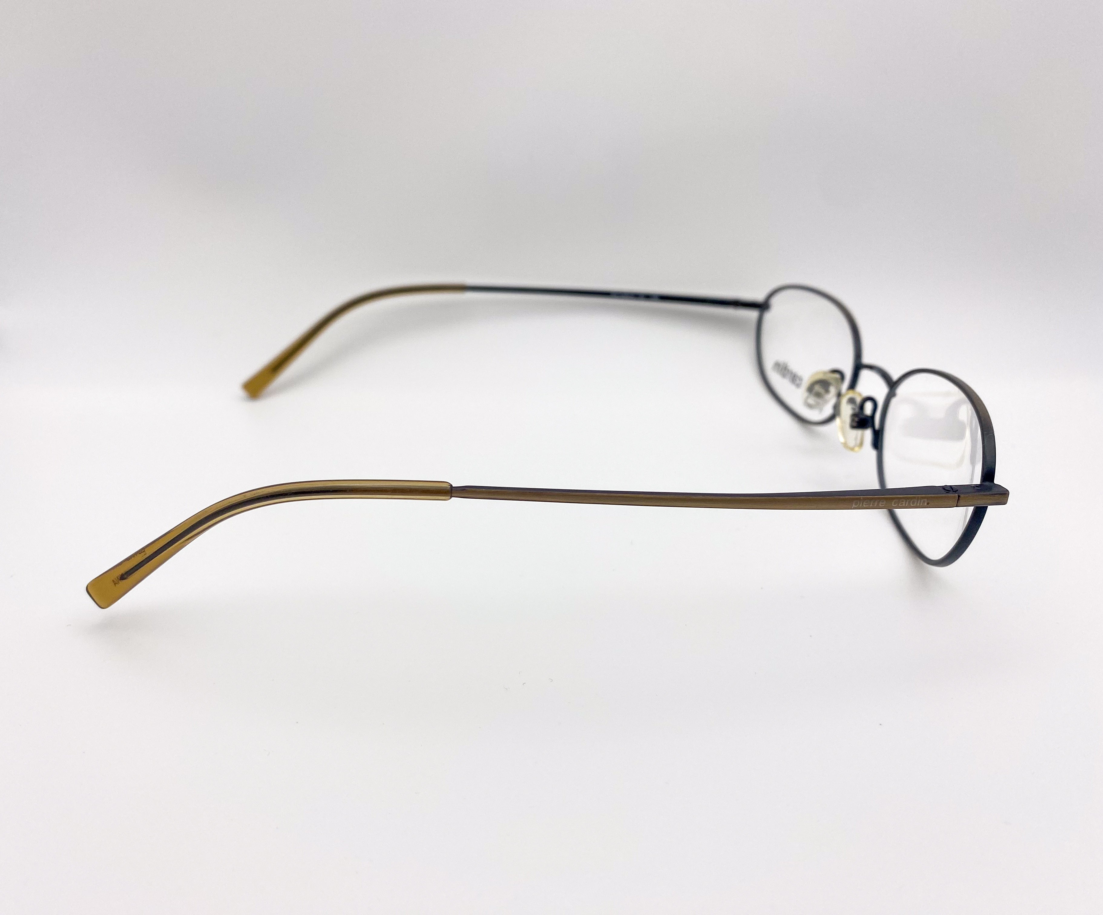 Pair of 1990s eyeglasses with gold frame and black arms on a white background