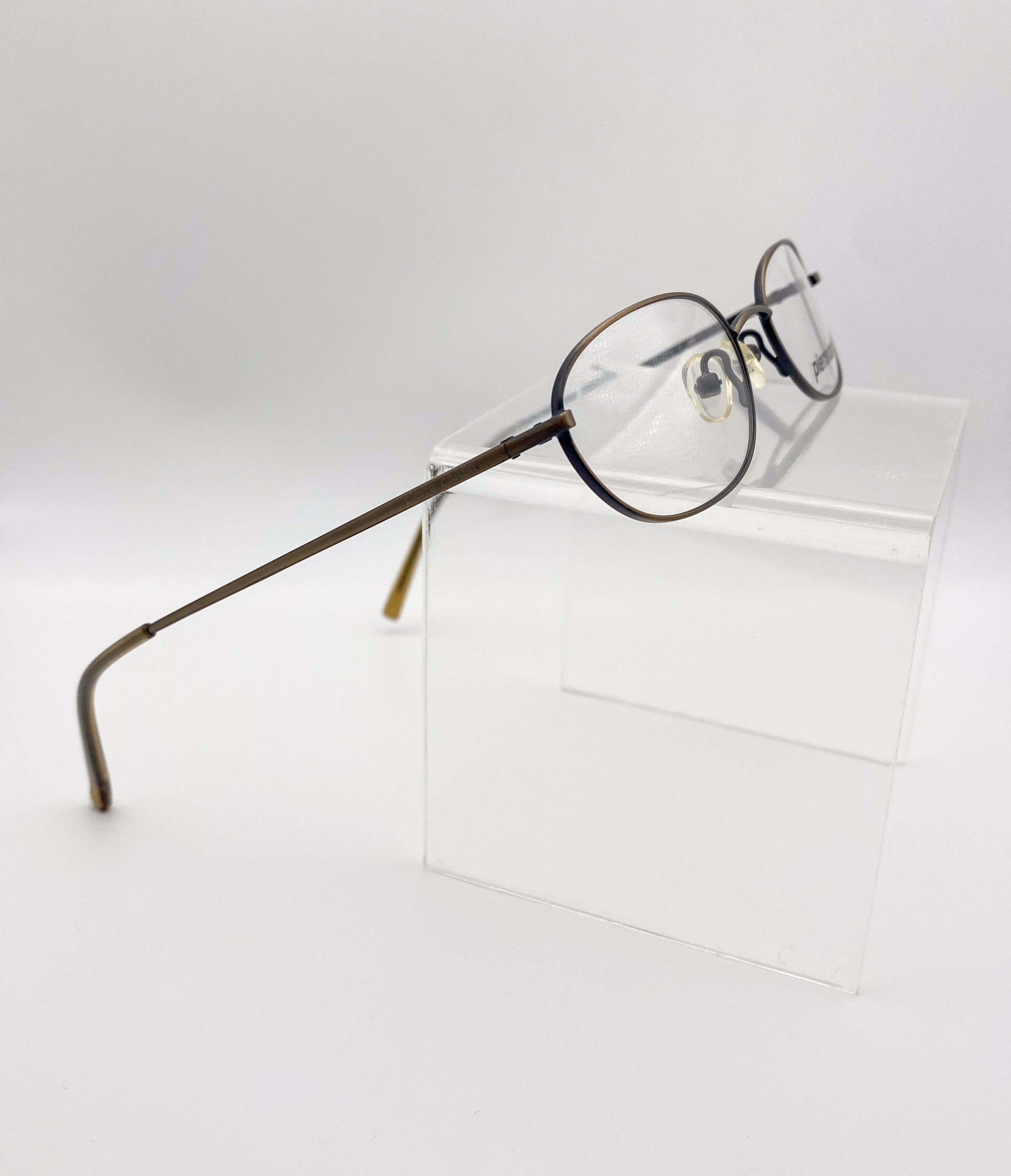 1990s eyeglasses on a clear stand against a white background