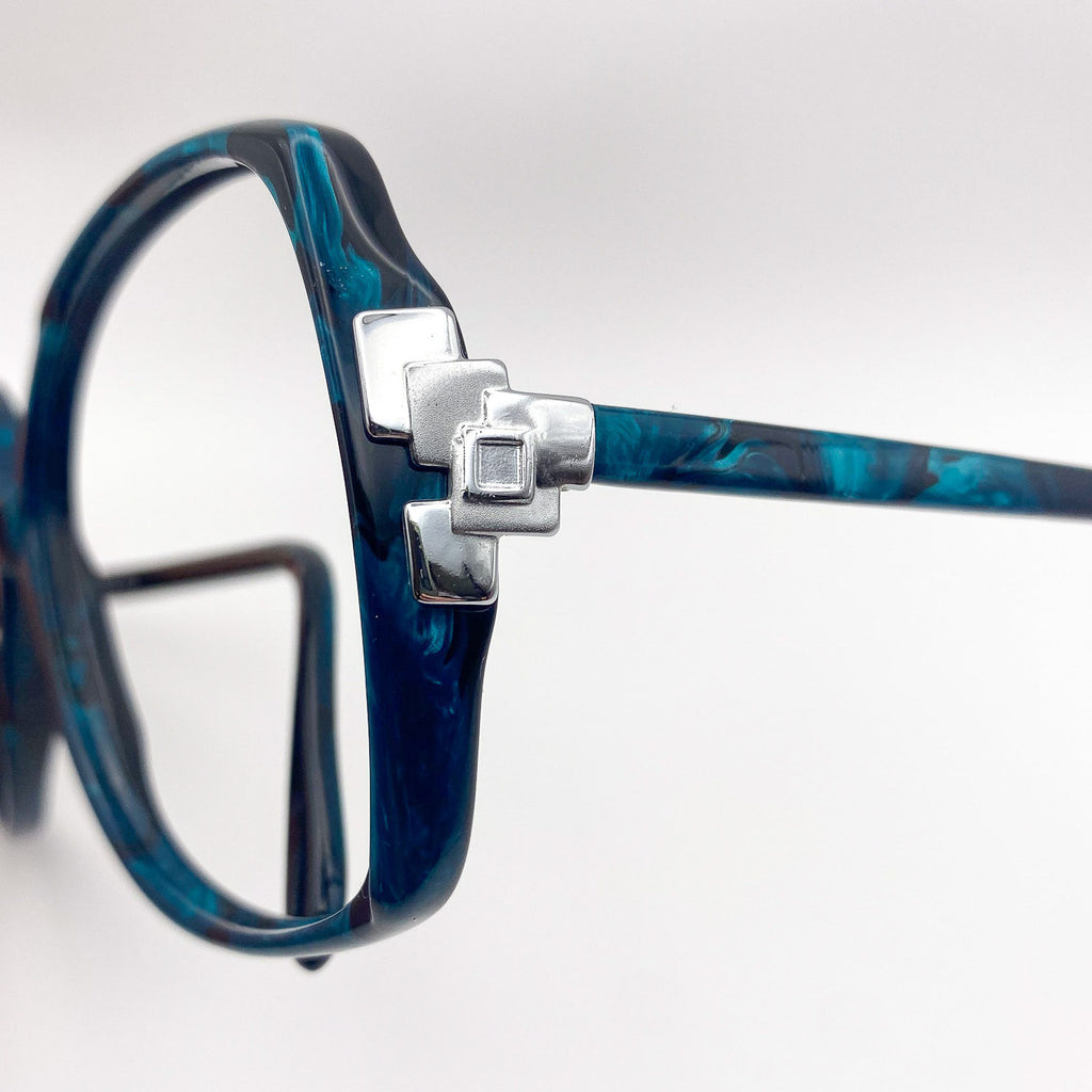 Close-up of a black eyeglasses frame with silver accent on a light gray background