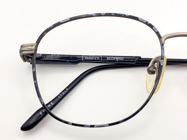 Close-up of a black eyeglasses frame with 'Gant' branding on a white background