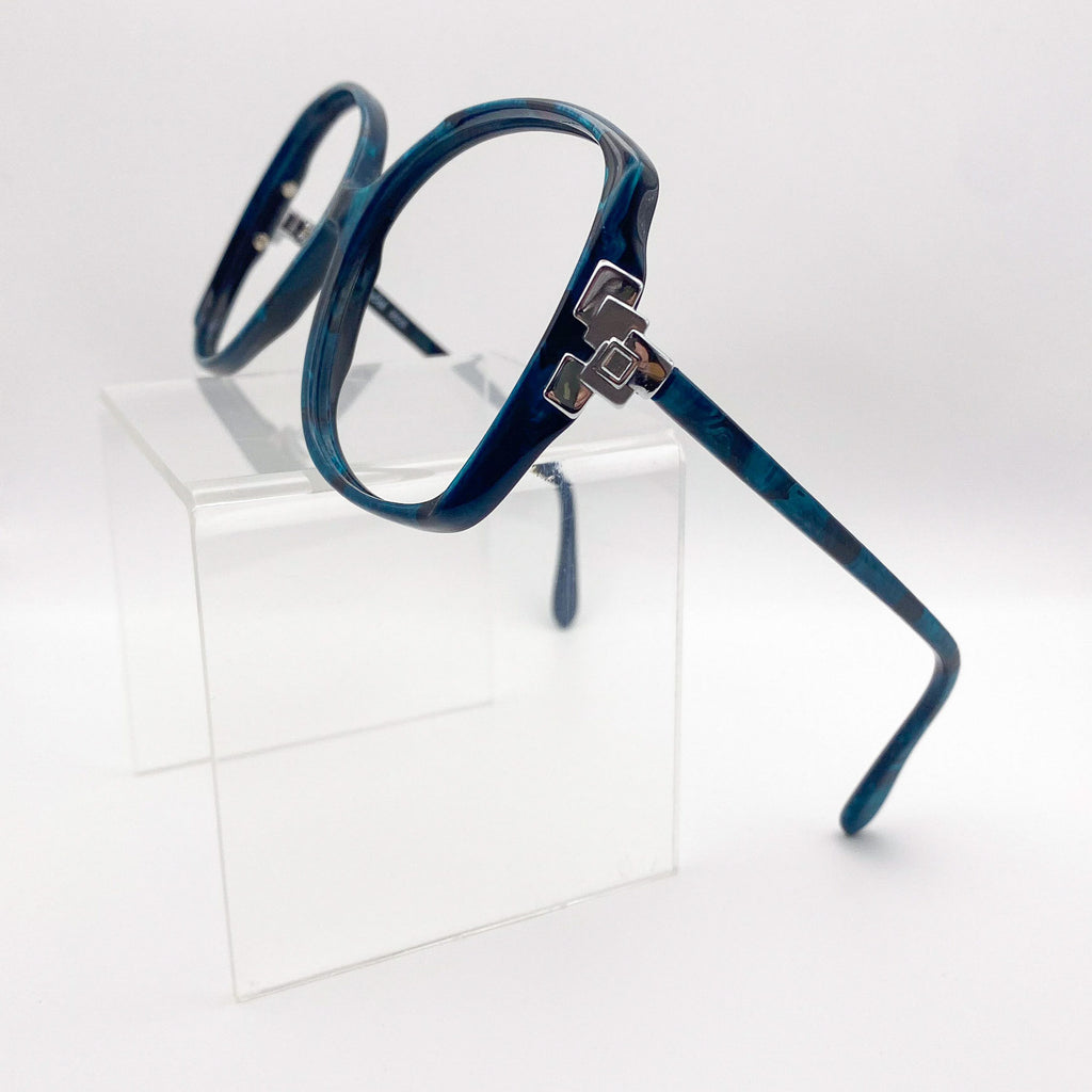 Side view of oversized butterfly glasses on a clear stand against a white background