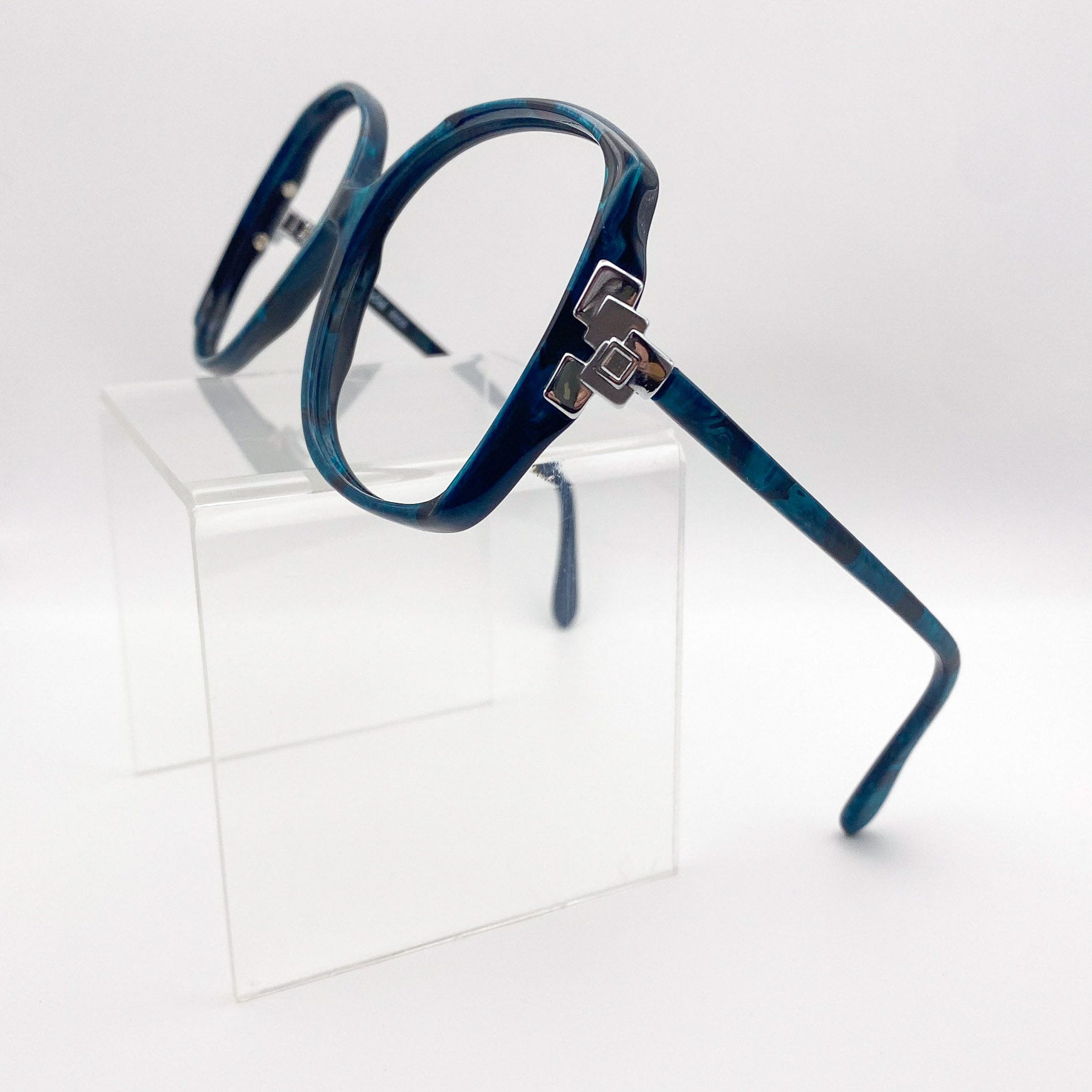 Side view of oversized butterfly glasses on a clear stand against a white background