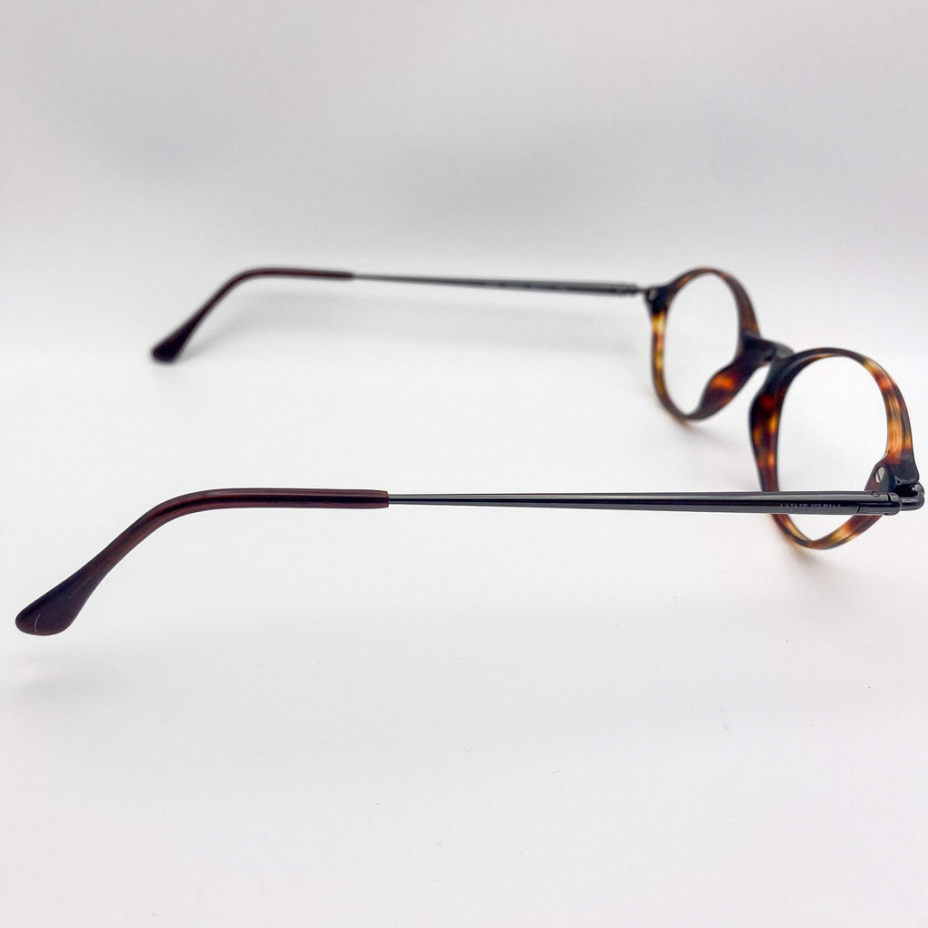 Pair of oval eyeglasses with tortoiseshell frame on a light gray background