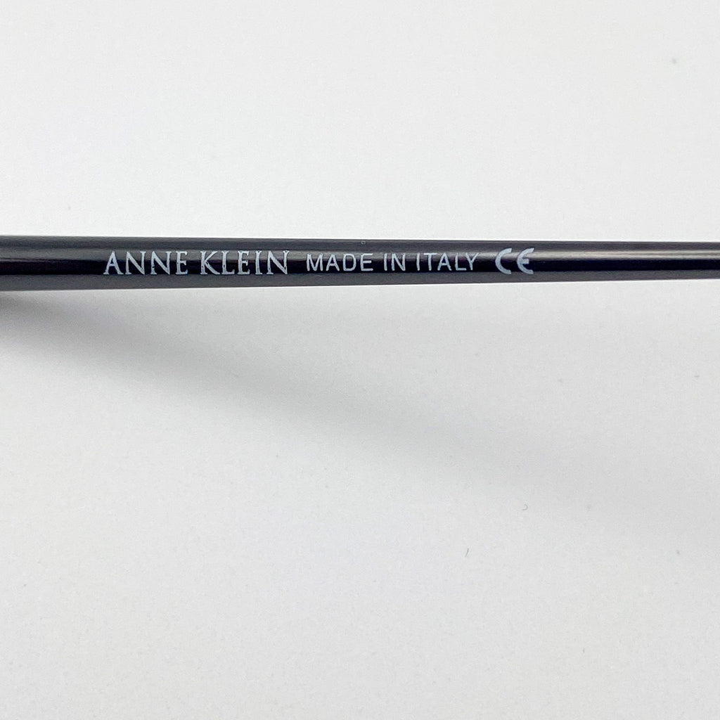 Black eyeglasses stem with 'Anne Klein' branding on a white background