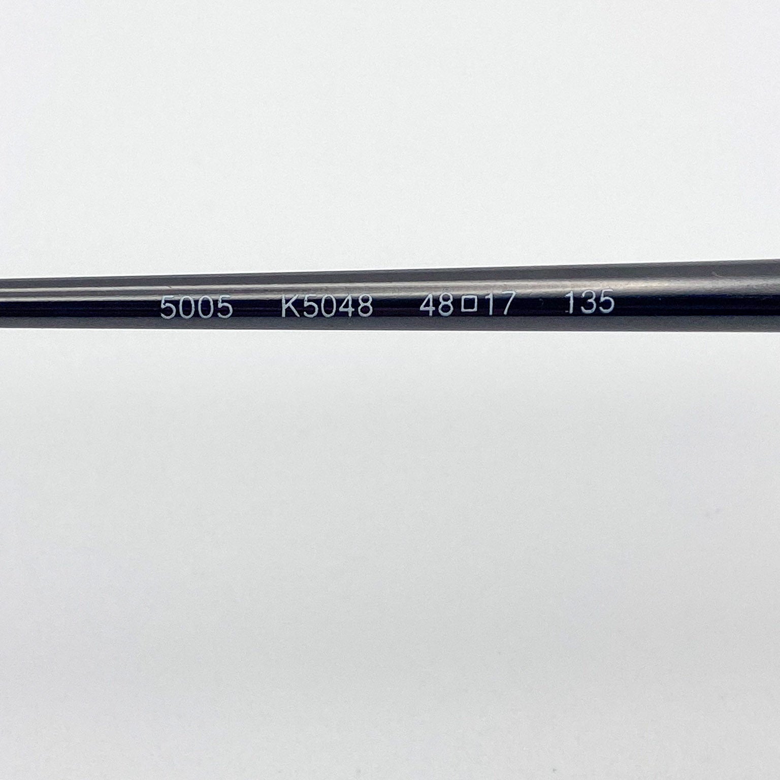 Close-up of a black eyeglass temple stem with engraved measurements on a white background