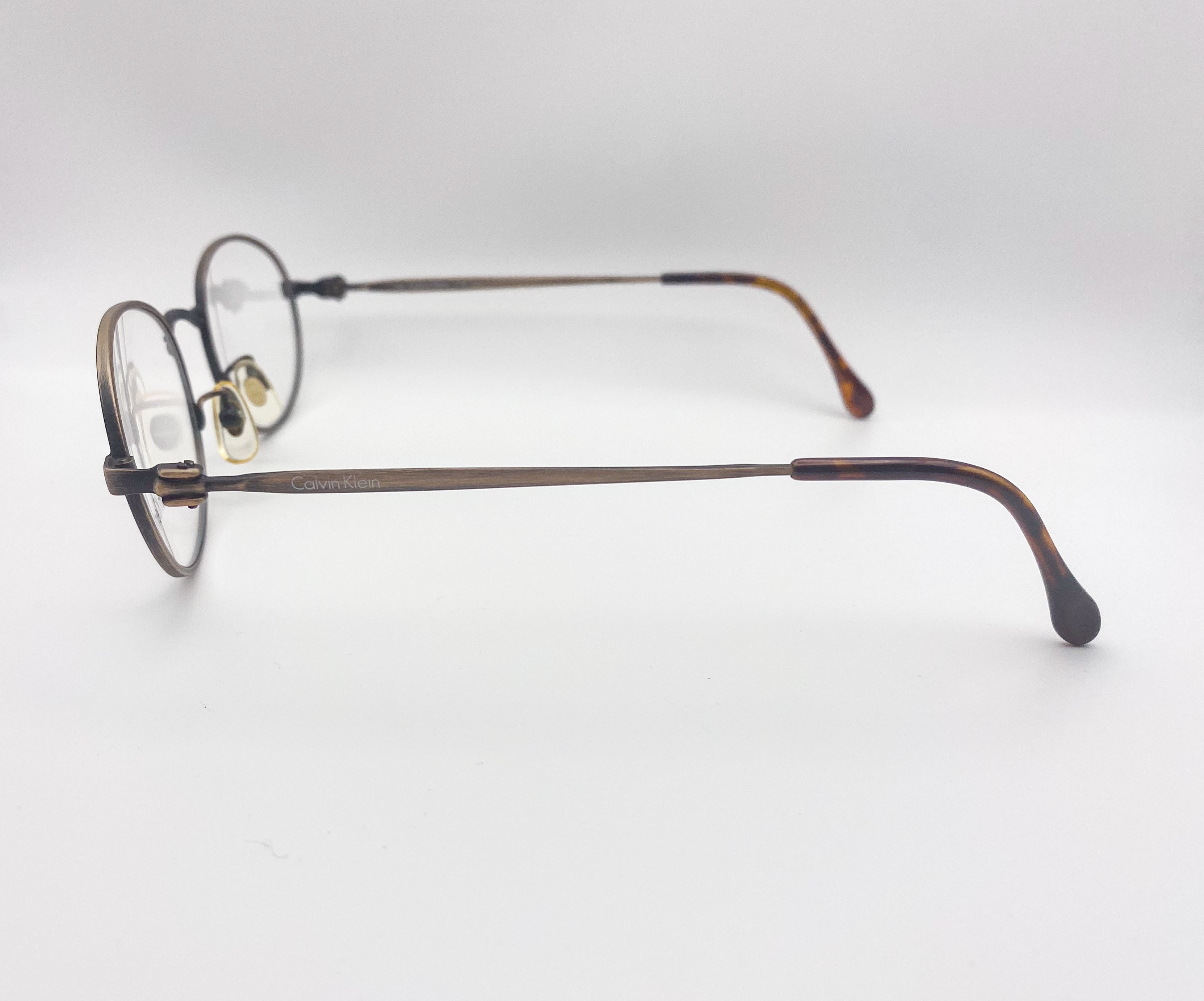 Pair of metal eyeglasses on a light gray background