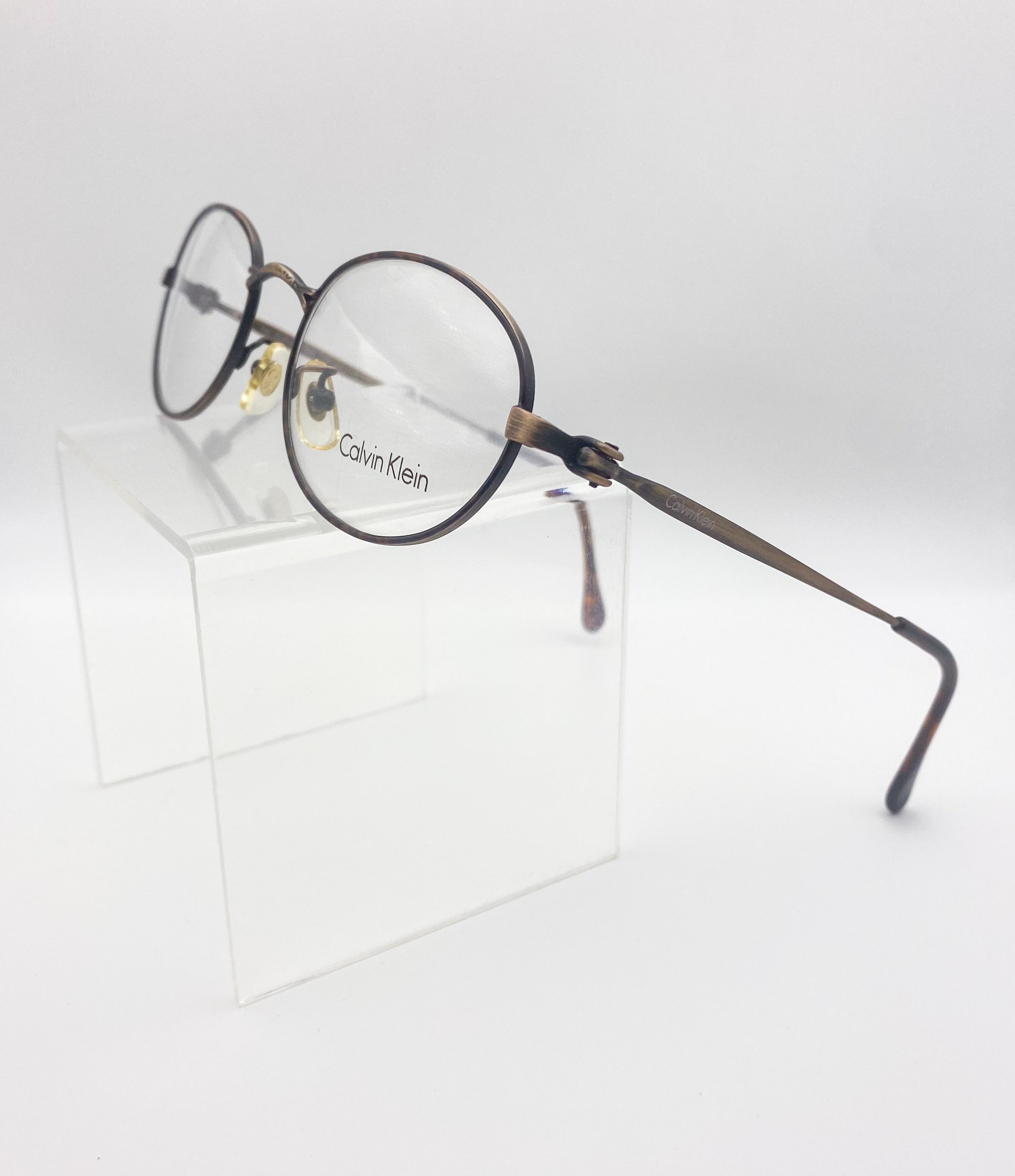 Round eyeglasses with 'Calvin Klein' logo on a white background