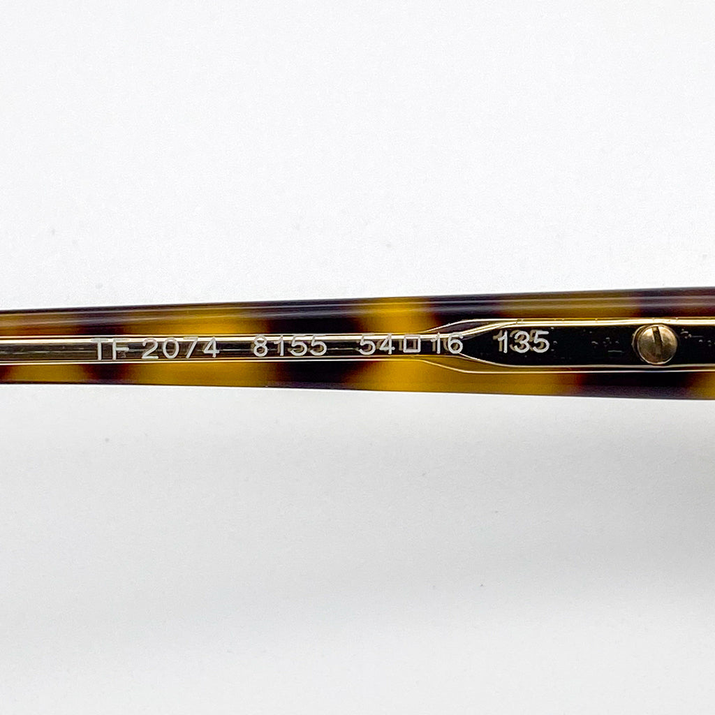 Close-up of a tortoiseshell eyeglass frame with gold accents on a white background