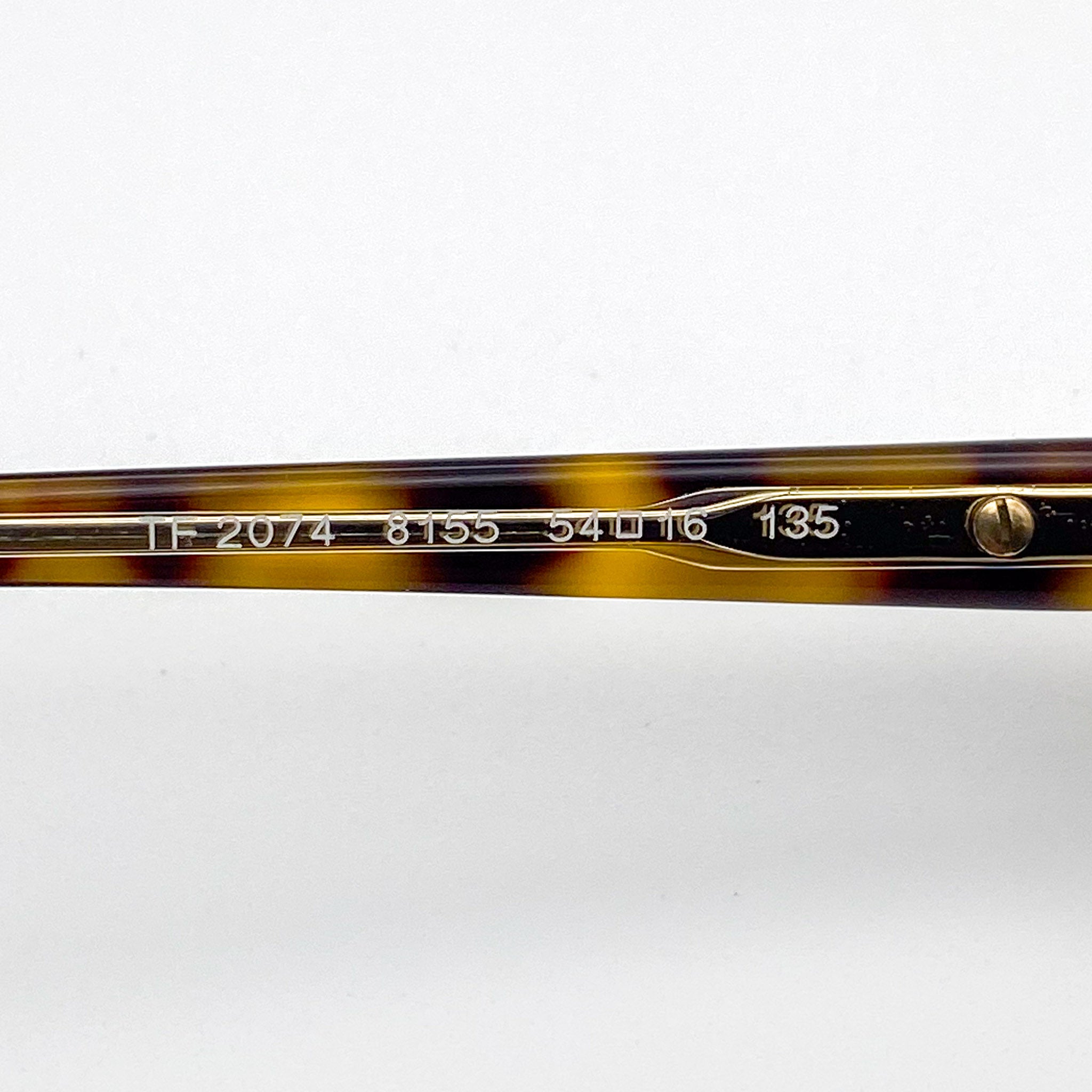 Close-up of a tortoiseshell eyeglass frame with gold accents on a white background