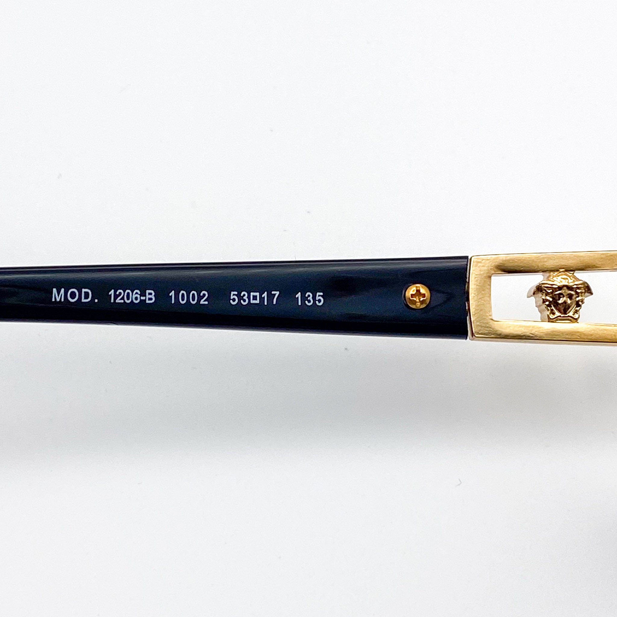 Eyeglass frame with gold and black design on a white background