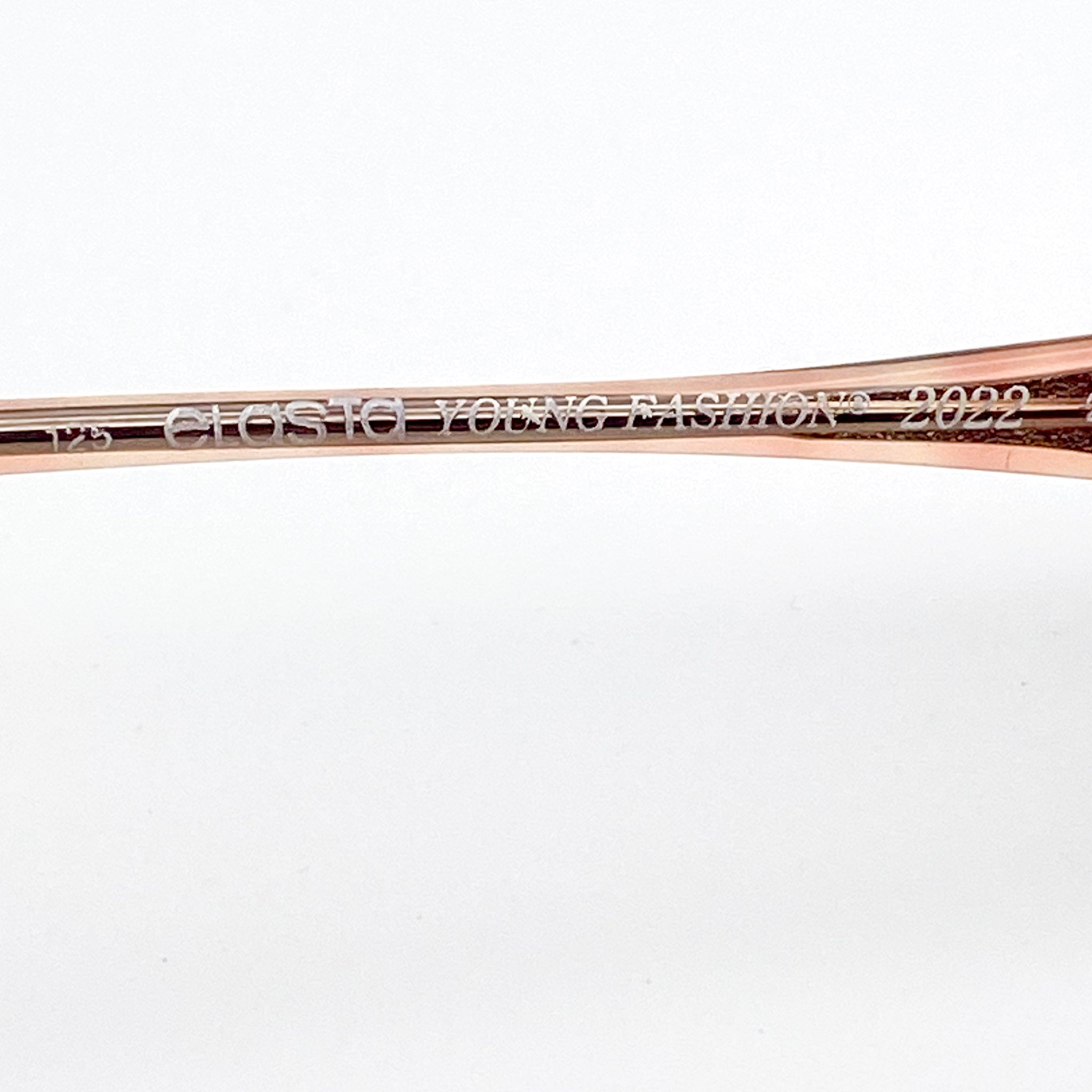 Close-up of eyeglasses with 'Elasta Young Fashion' branding on a white background