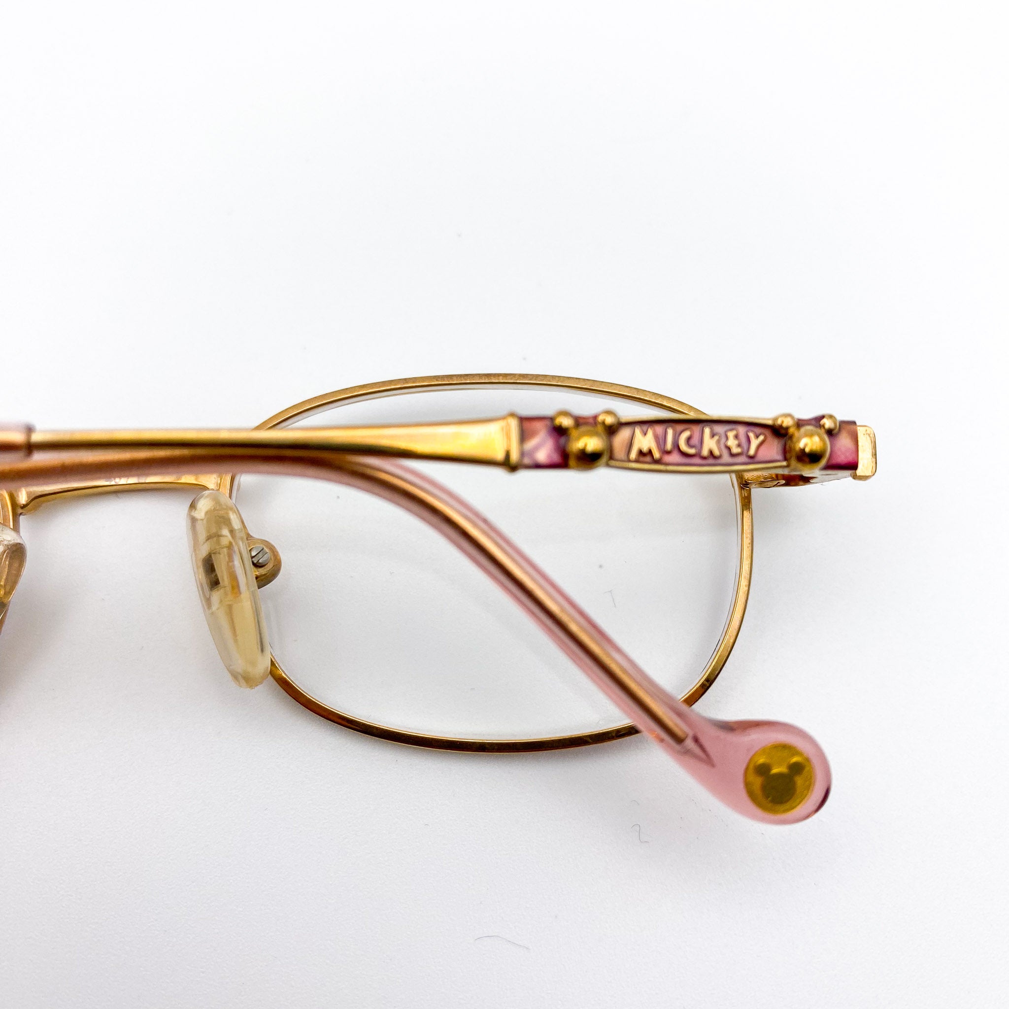 Gold-rimmed eyeglasses with 'Mickey' branding on a white background