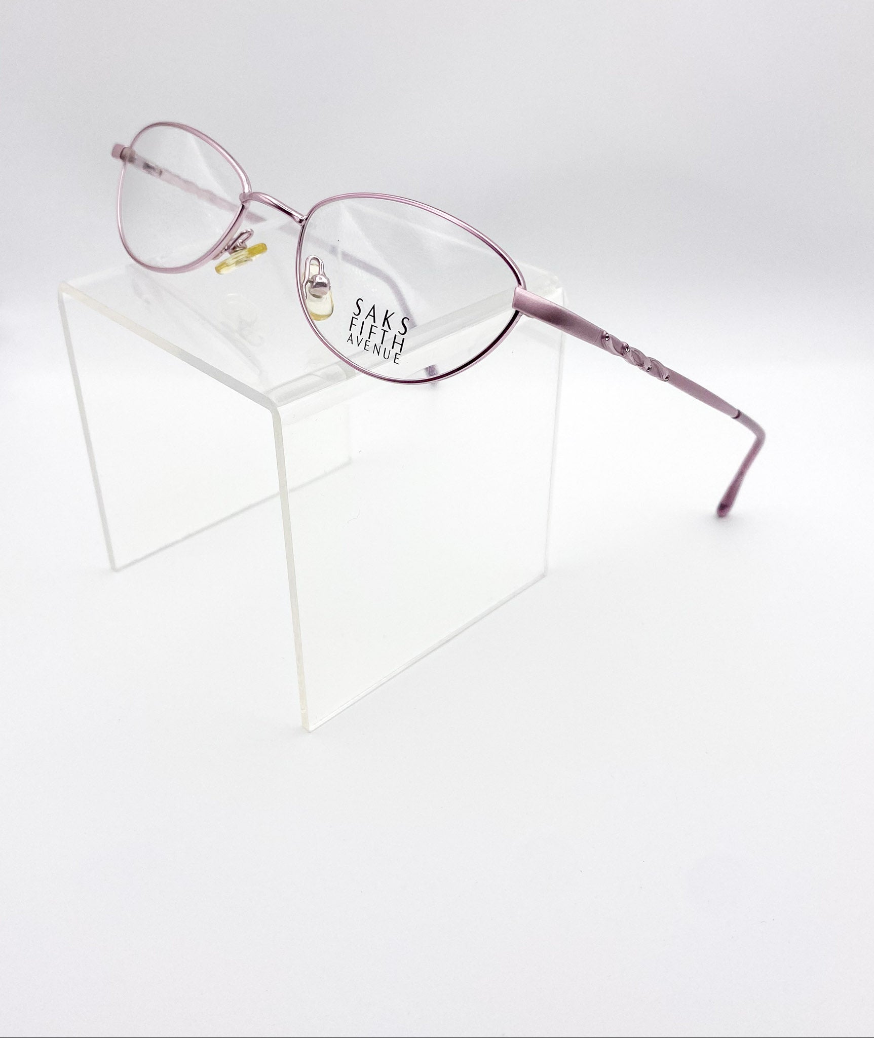 Lavender eyeglasses on a white background with 'Saks Fifth Avenue' branding.