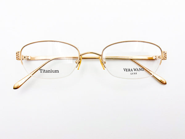 Gold-framed glasses with 'Vera Wang' branding on a white background