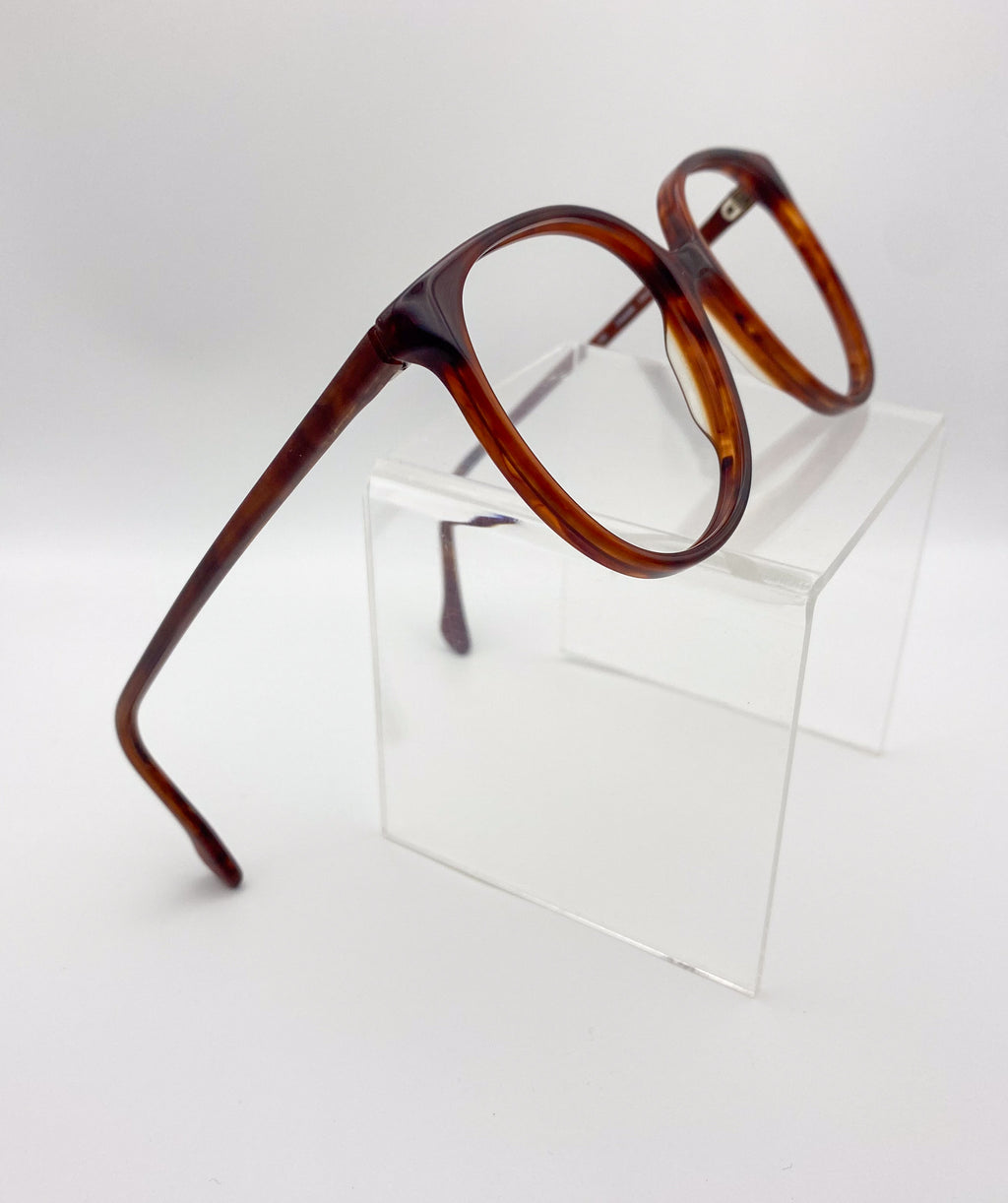Tortoiseshell eyeglasses on a clear stand against a white background