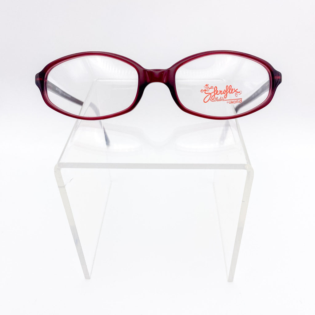 Red eyeglasses on a clear stand against a white background