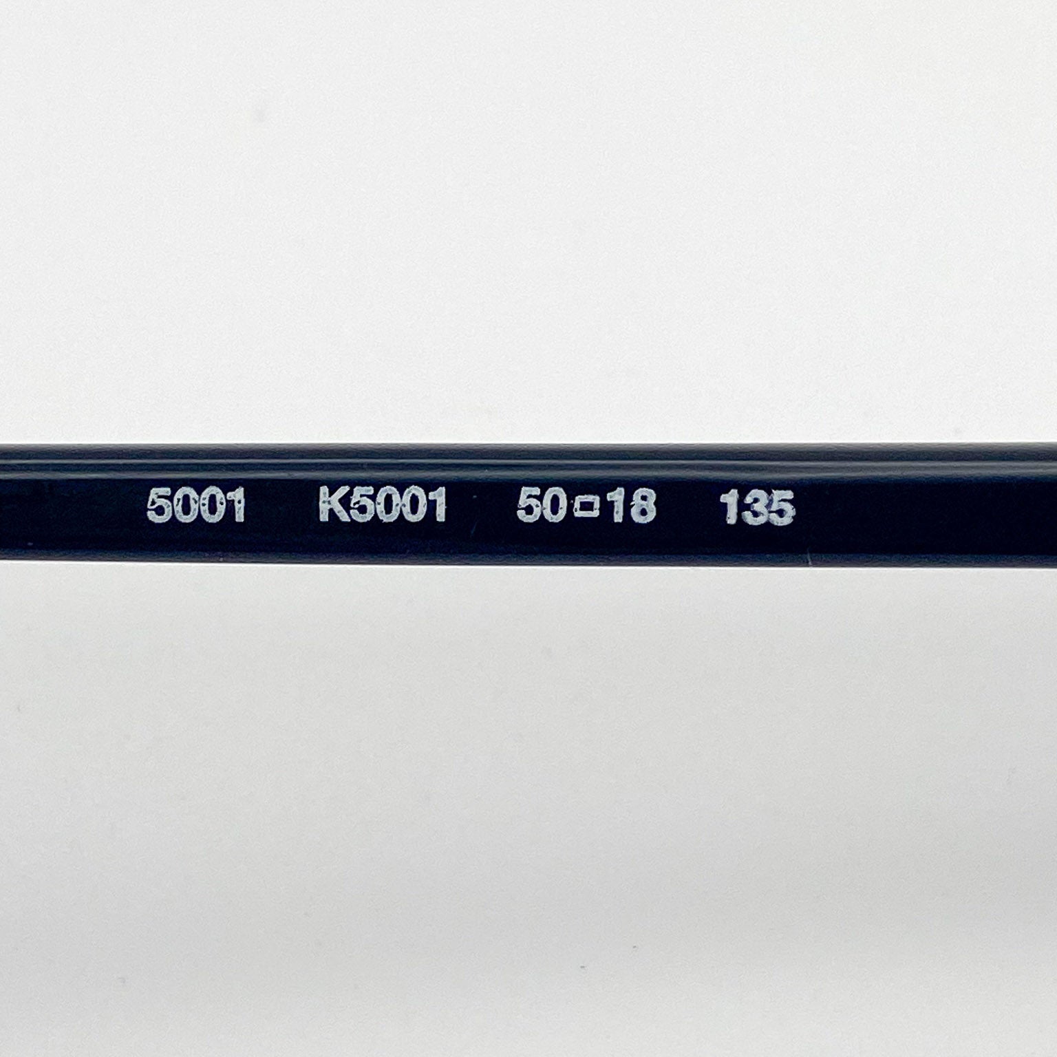 Close-up of an eyeglasses temple with engraved text on a white background