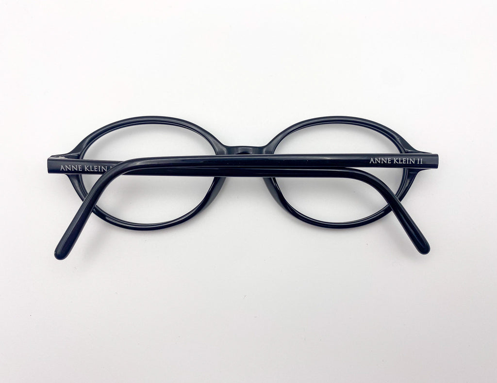 Black eyeglasses with 'Anne Klein' branding on a white background