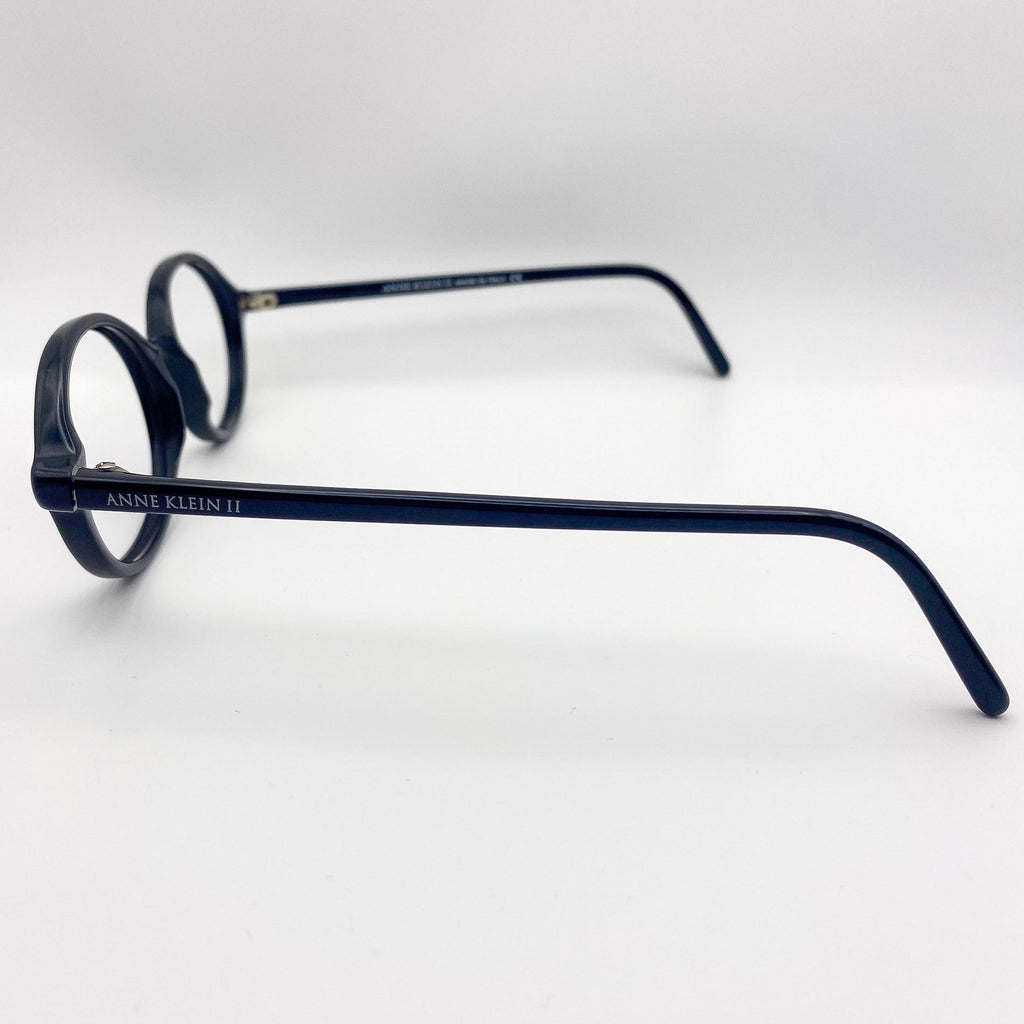 Black eyeglasses with 'Anne Klein' branding on a white background