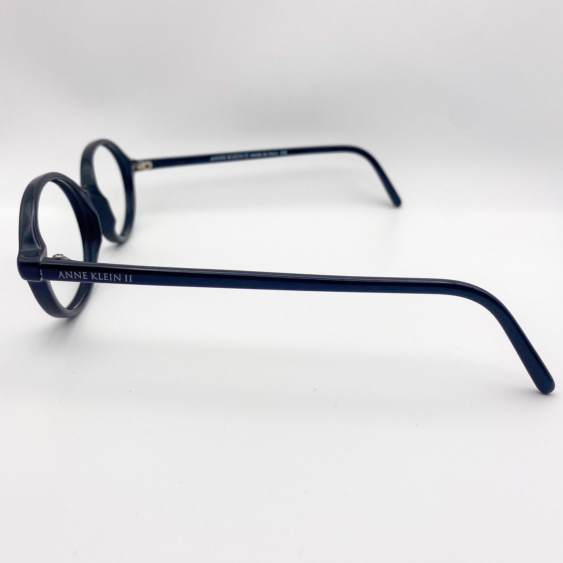Black eyeglasses with 'Anne Klein' branding on a white background