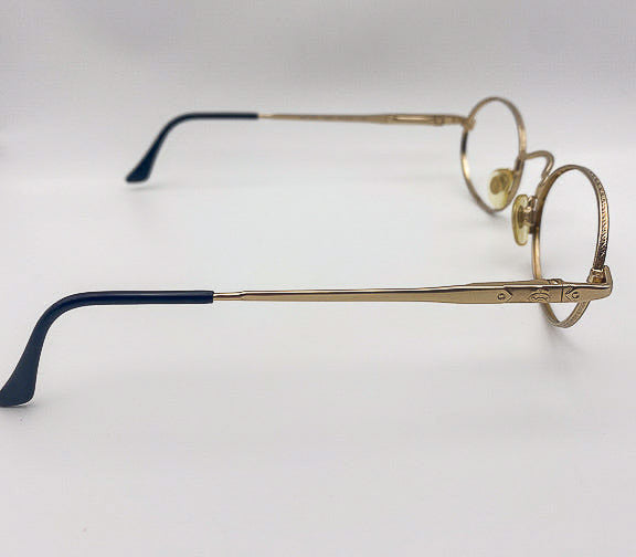 Pair of eyeglasses with gold frame and black arms on a white background