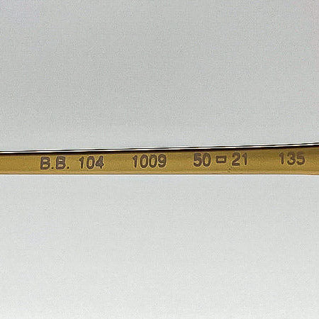 Gold-colored temple stem with engraved text on a white background