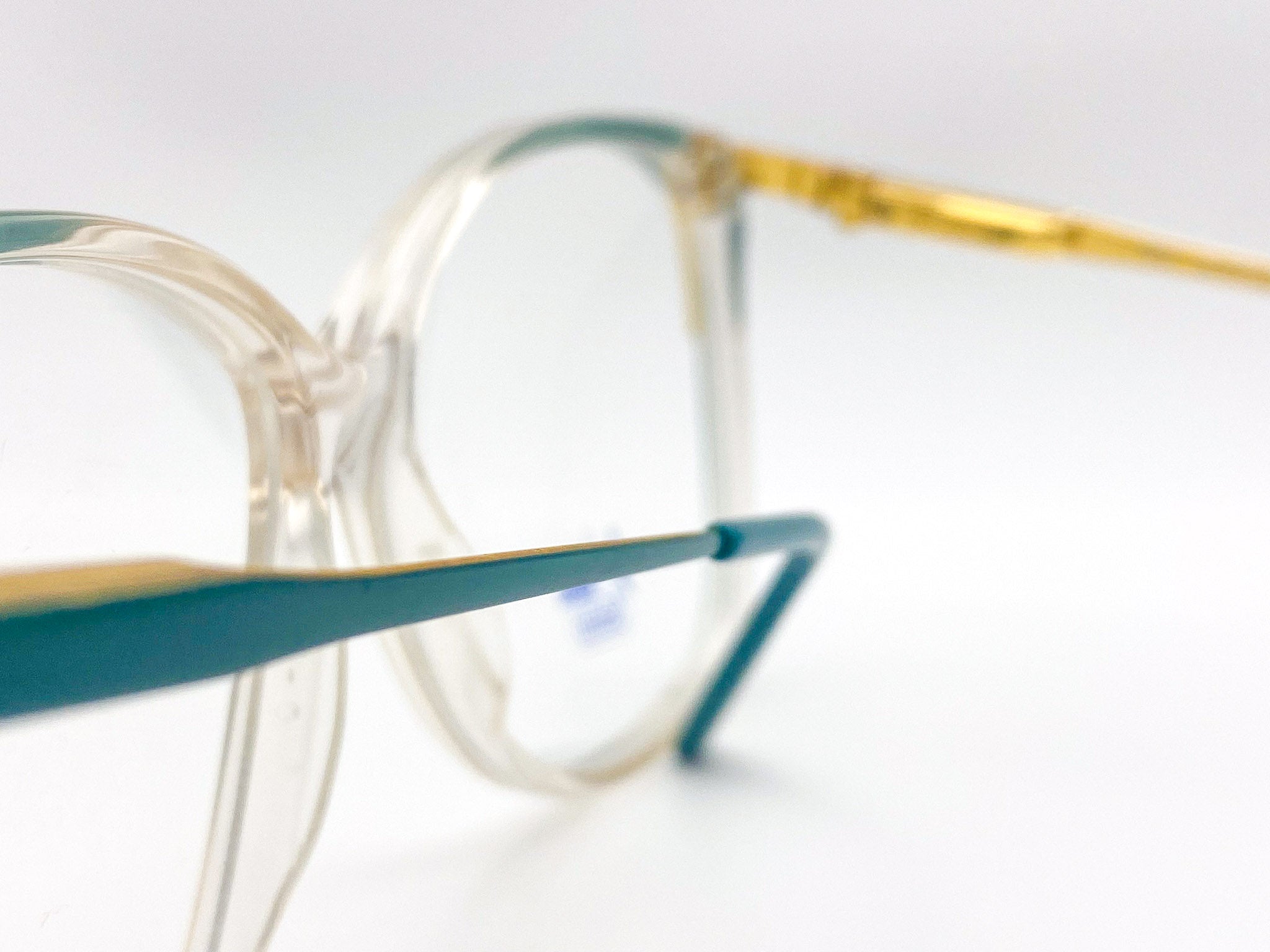 Close-up of vintage eyeglasses with gold and green frames on a light background