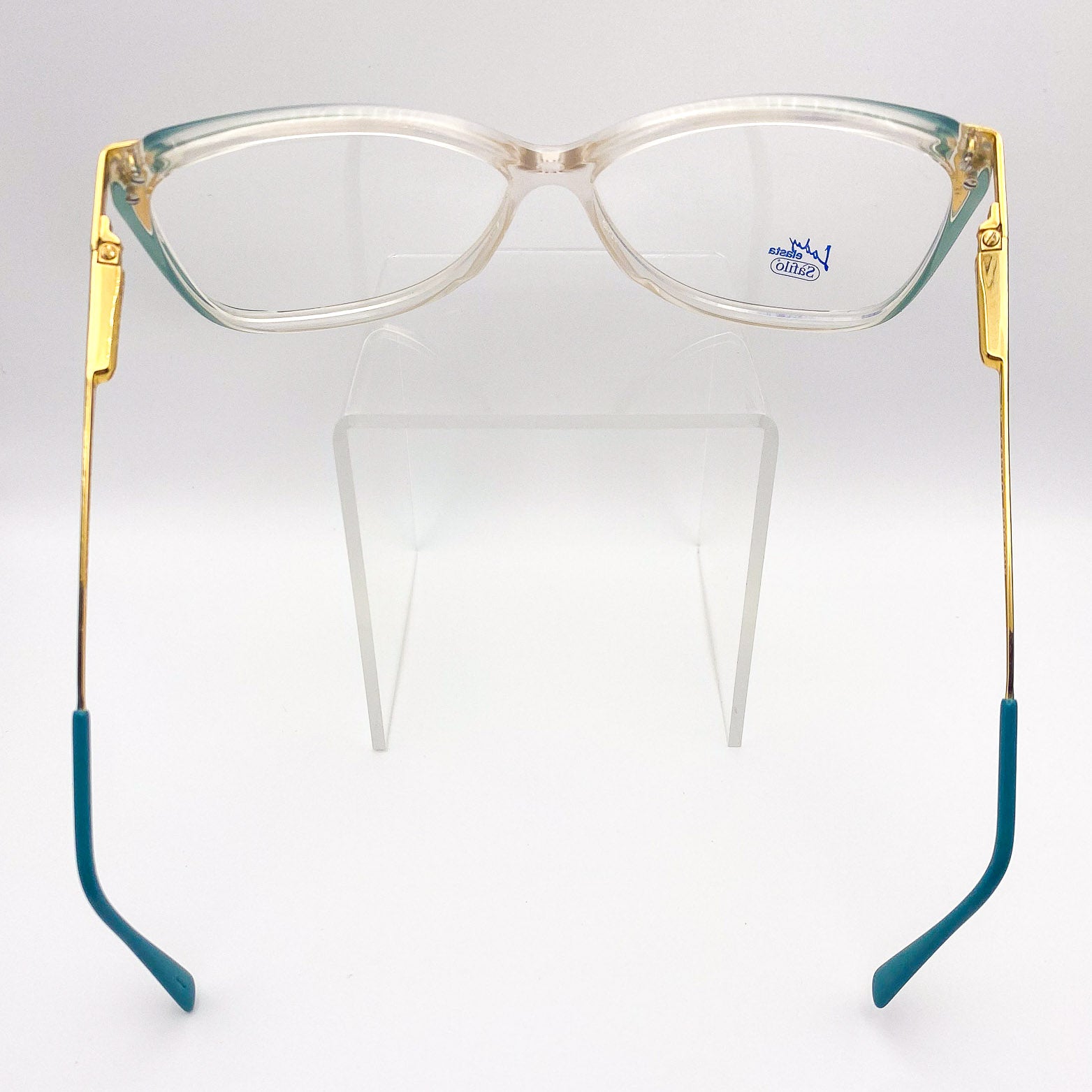 Eyeglasses with gold and green temple tips on a white background