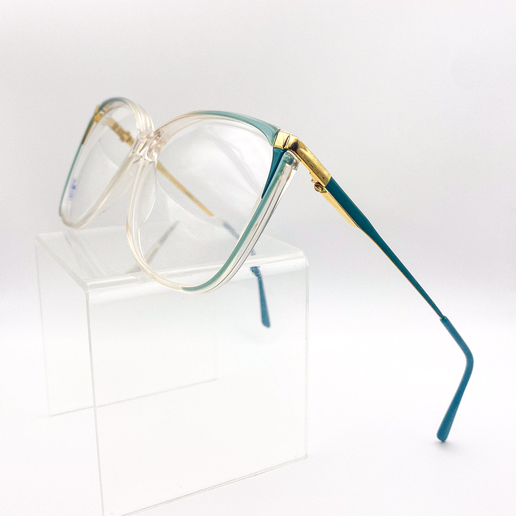 1980s eyeglasses with gold and teal frame on a white background