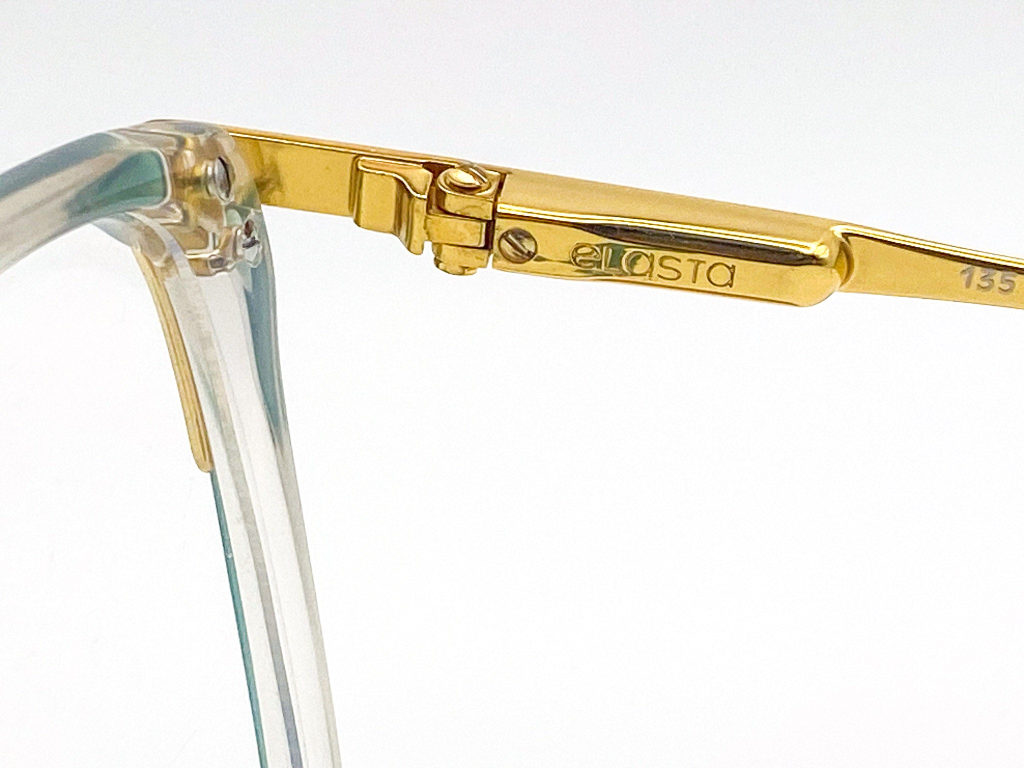 Gold-framed eyeglasses with 'elasta' branding on a white background