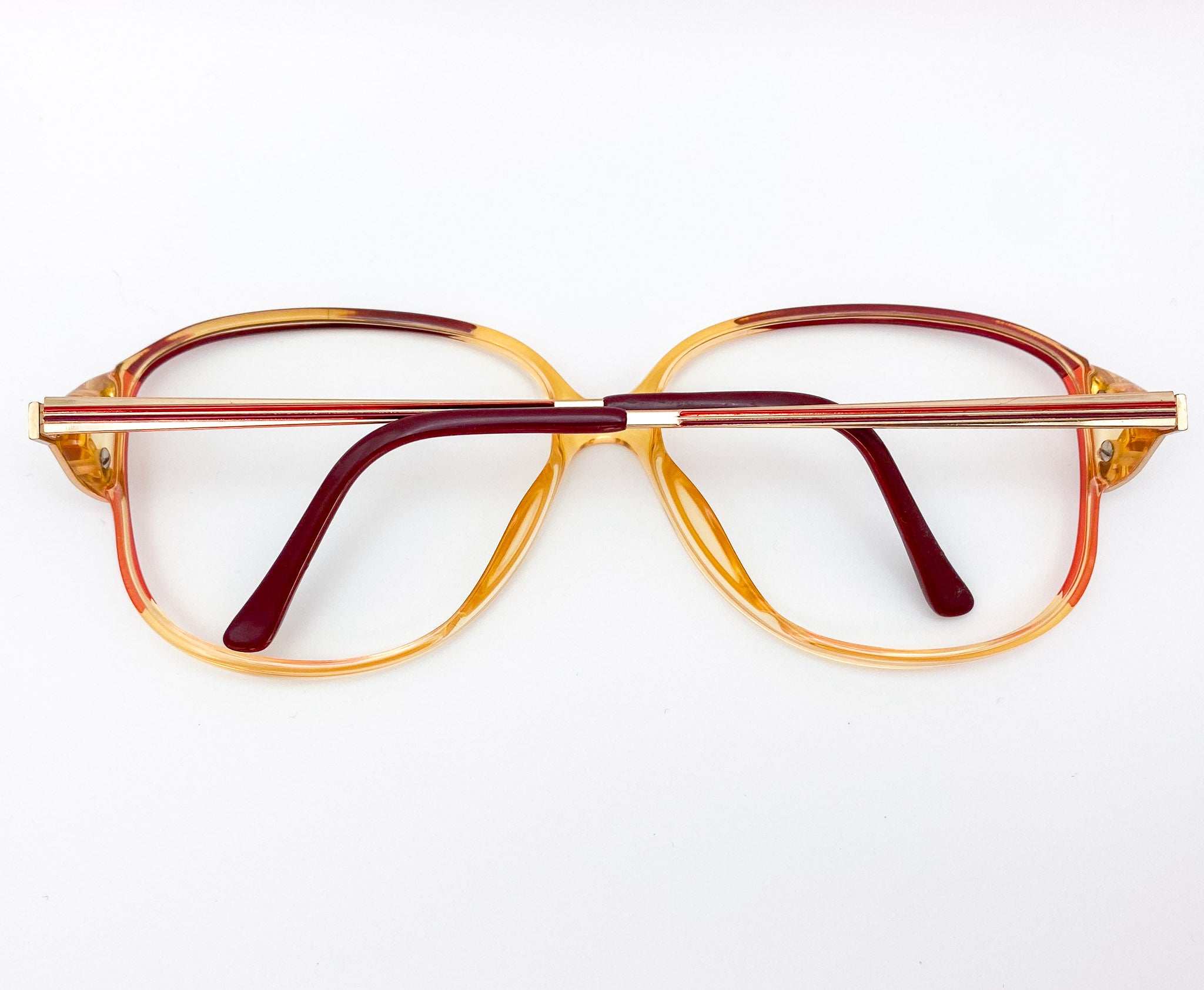 Vintage-style eyeglasses with a gold and red frame on a white background