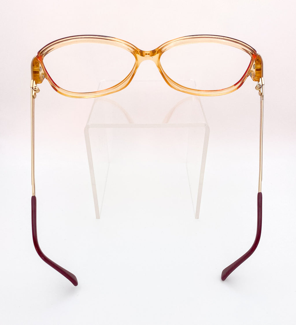 Eyeglasses with a transparent orange frame and burgundy arms on a white background