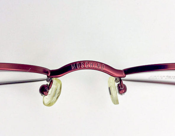 Vintage red Moschino eyeglass frame with gold lenses on a white background