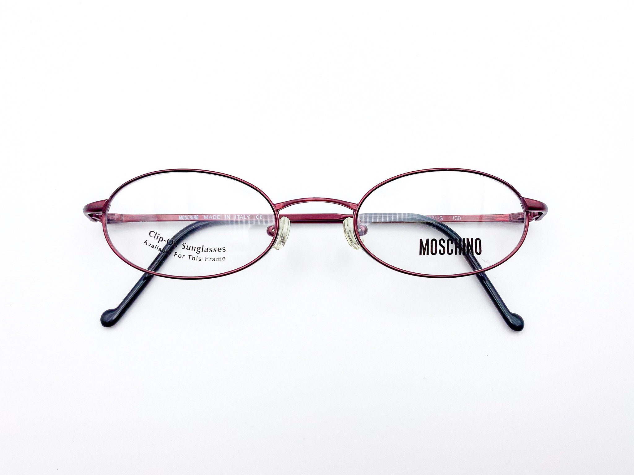 Oval red eyeglasses with black temples on a white background, featuring the Moschino logo.