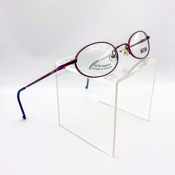 1990s eyeglasses with burgundy frame on a clear stand against a white background