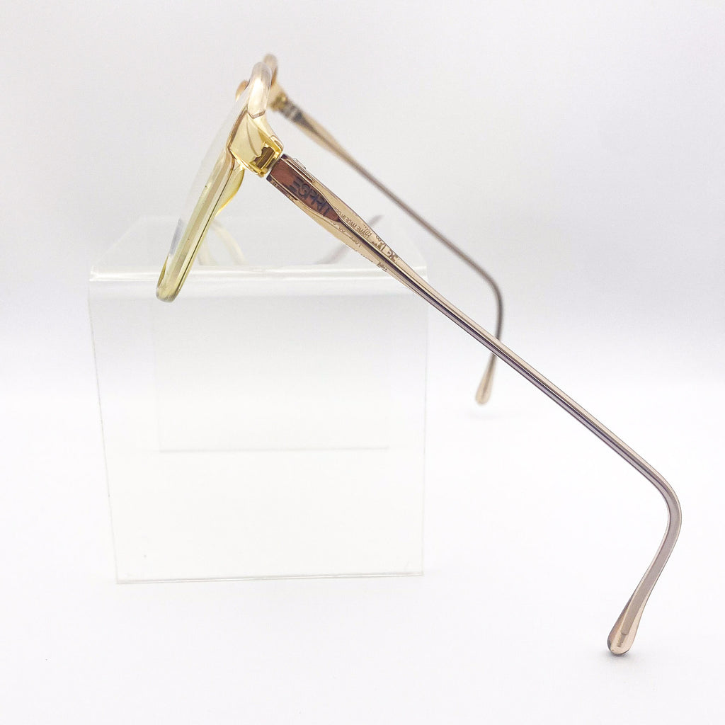 Translucent yellow eyeglasses on a clear stand against a white background