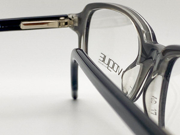 Close-up of a pair of eyeglasses with a visible brand logo on a light background