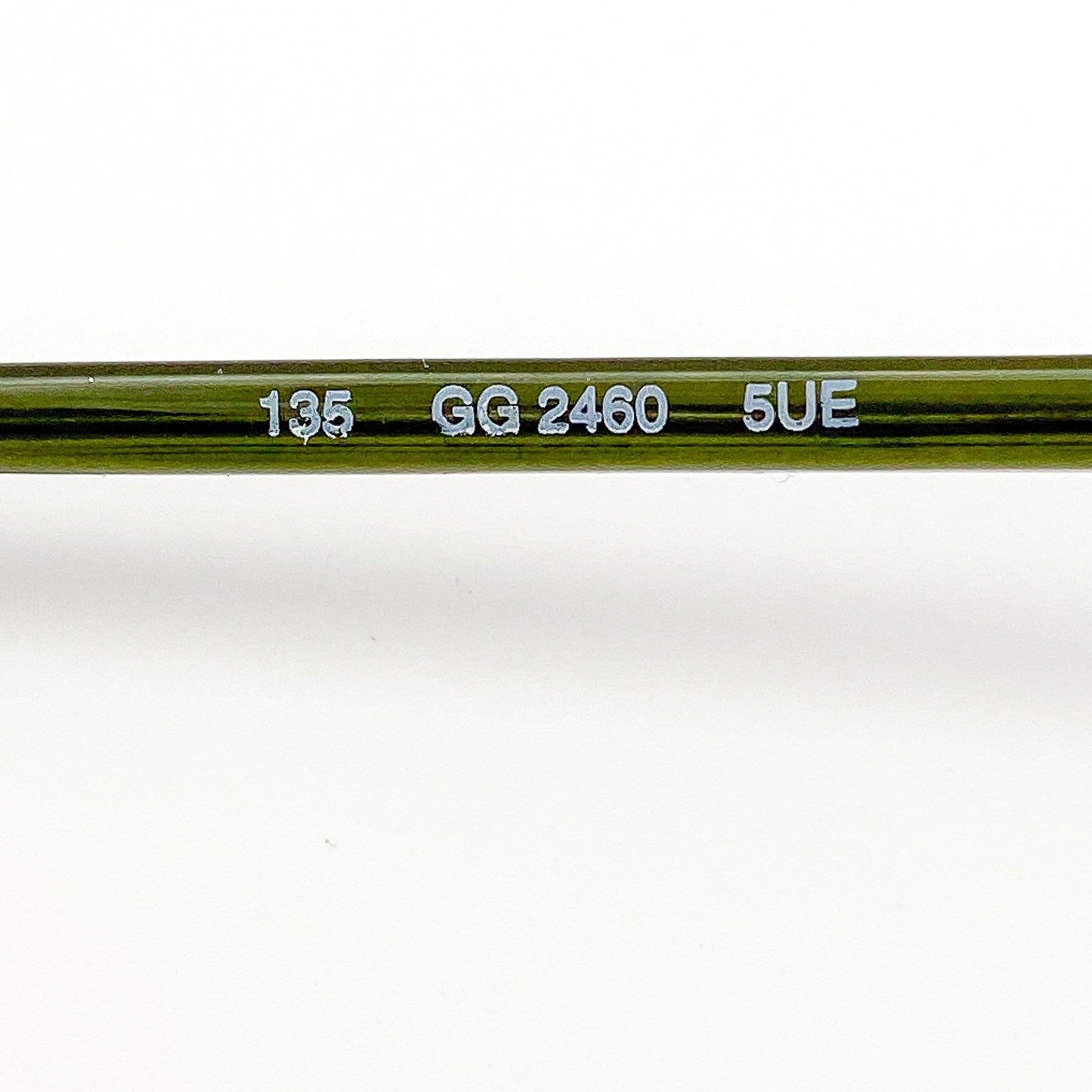 Close-up of a green eyeglasses with engraved text on a white background