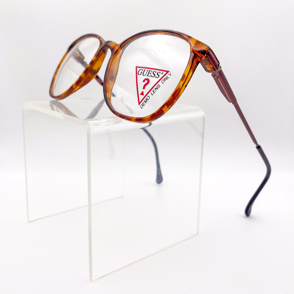 Tortoiseshell eyeglasses with Guess logo on a white background