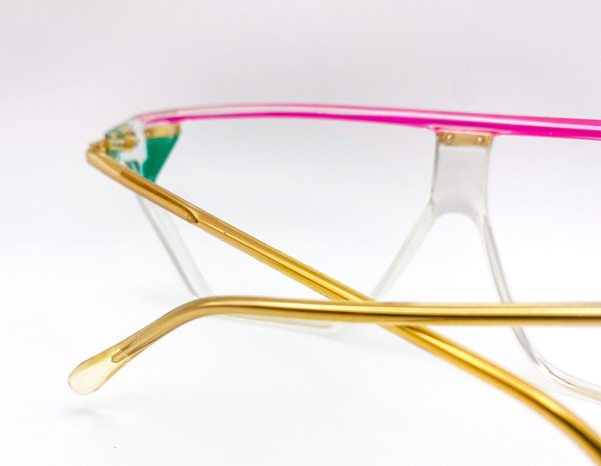 Eyeglasses with gold frame and pink interior on a white background