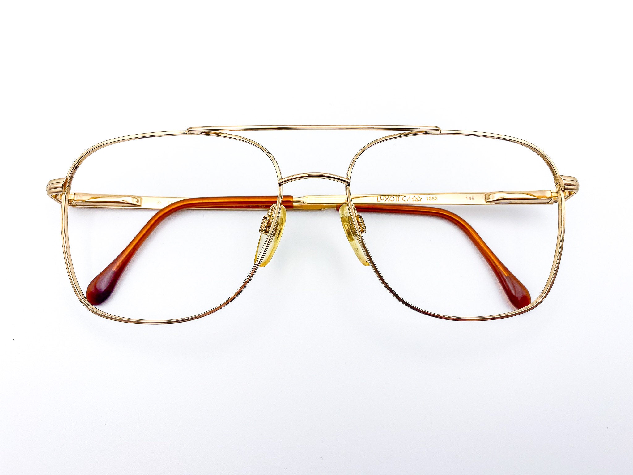 Vintage Luxottica gold-framed eyeglasses with brown temple tips on a white background