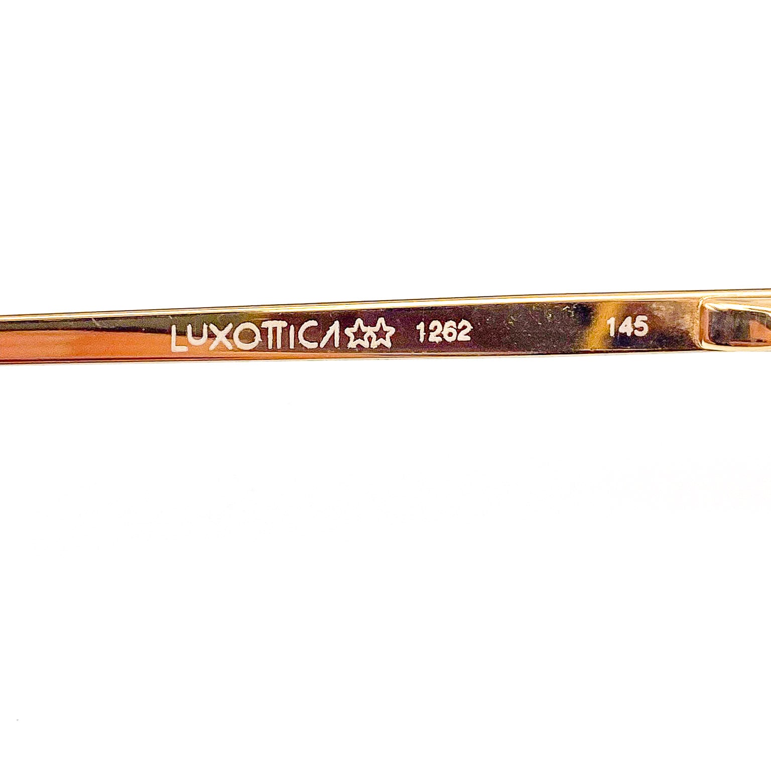 Close-up of a gold eyeglass frame with 'Luxottica' branding on a white background